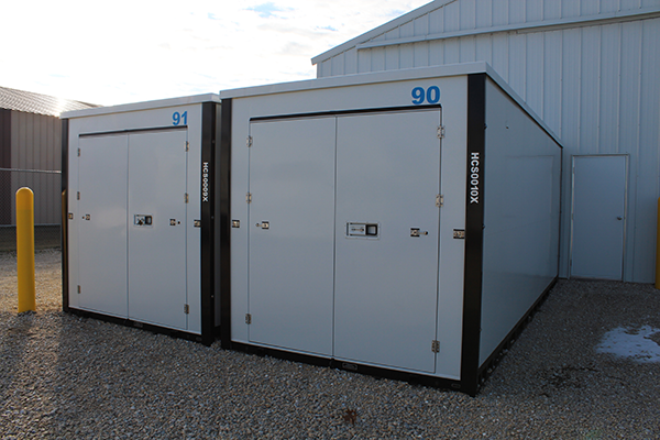 A couple of white storage containers sitting on top of gravel.